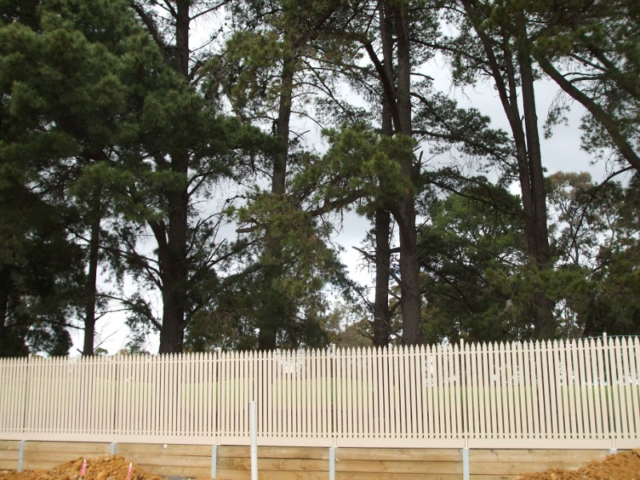 Cream steel picket fence on retaining wall