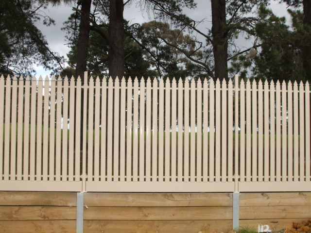 Cream steel picket fence on retaining wall